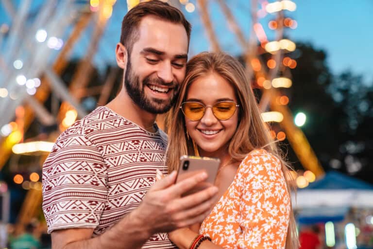 theme park reservations Couple-using-mobile-phone-in-theme-park