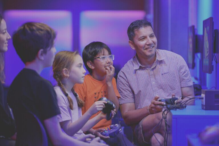 Families and friends enjoying a 4-player game in Power Up, the Science Museum’s hands-on gaming experience
