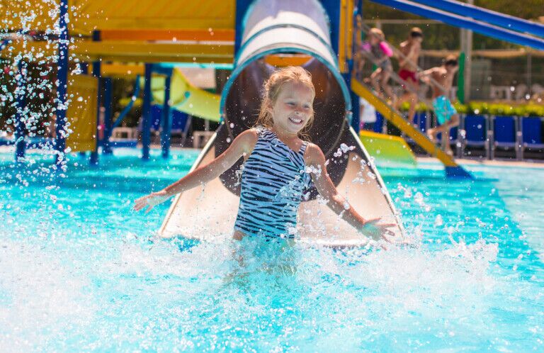 Kid on water slide at aquapark at summer holiday